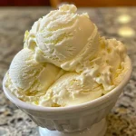 Detailaufnahme von selbstgemachtem No-Churn Zitroneneis in einer Eisschale.