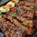 Grillierte Rindfleisch-Spieße mit Garnitur aus Sesam und Frühlingszwiebeln.