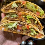 Nahaufnahme eines Crunch Wraps mit glänzender Oberfläche und leckerer Füllung.