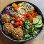 Nahaufnahme eines Falafel-Bowls mit frischem Gemüse und Couscous.