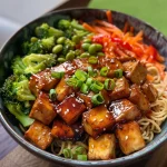 Eine Nahaufnahme eines veganen Teriyaki-Nudel-Bowls mit buntem Gemüse und Tofu.