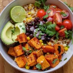 Nahaufnahme eines veganen Süßkartoffel-Burrito-Bowls mit bunten Zutaten.