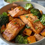 ['Close-up view of a maple salmon bowl featuring wild-caught salmon, sweet potato, and broccoli.', 'Side angle photo of a vibrant salmon bowl with chunks of salmon, diced sweet potatoes, and green broccoli.', 'Deliciously arranged maple salmon bowl showcasing roasted sweet potatoes and broccoli.', 'Colorful presentation of maple salmon dish, highlighting the salmon, sweet potatoes, and broccoli.']
