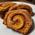 ['Close-up of a freshly baked healthy pumpkin cinnamon roll, showcasing its fluffy texture and golden-brown color.', 'Side view of healthy pumpkin cinnamon rolls drizzled with a light glaze, highlighting the cinnamon and pumpkin elements.', 'Image of a delicious pumpkin cinnamon roll on a plate, revealing the swirls of cinnamon and the soft dough.', 'Detailed view of a healthy pumpkin cinnamon roll, emphasizing its moist interior and rich topping.']