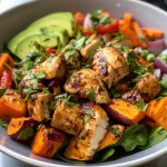 ['A colorful bowl featuring chicken pieces, sweet potatoes, and fresh vegetables.', 'Close-up view of a chicken and sweet potato bowl topped with avocado slices.', 'A side view of a nutritious chicken bowl filled with vibrant vegetables and seasonings.', 'Juicy chicken and sweet potato bowl garnished with spinach and lime dressing.']