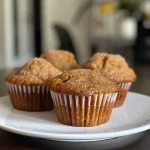 ['Close-up view of moist pumpkin banana muffins with a golden-brown crust.', 'Side angle of freshly baked pumpkin banana muffins, showcasing their delicious texture.', 'Juicy Kürbis Bananen Muffins arranged on a plate, highlighting their fluffy interior.', 'Detailed shot of pumpkin banana muffins, emphasizing the cinnamon-spiced topping.']