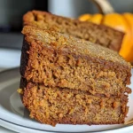 ['Close-up view of freshly baked pumpkin banana bread with a golden crust.', 'Side view of a slice of pumpkin banana bread showcasing its moist texture.', 'Juicy pumpkin banana bread with visible banana pieces and spices.', 'Delicious slice of Kürbis Bananenbrot, highlighting its rich color and ingredients.']