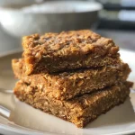 ['Close-up side view of pumpkin oatmeal bars with a golden-brown crust.', 'Juicy pumpkin oatmeal bars displayed on a rustic wooden surface.', 'Deliciously layered pumpkin oatmeal bars showcasing oats and pumpkin puree.', 'Freshly baked pumpkin oatmeal bars highlighting the texture and ingredients.']