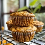['Close-up side view of a moist pumpkin protein muffin with a golden-brown top.', 'A delicious pumpkin protein muffin displayed on a rustic wooden surface.', 'Fluffy pumpkin muffin with a textured surface and a hint of spices visible.', 'Side view of a baked pumpkin muffin, showcasing its soft interior and crispy edges.']