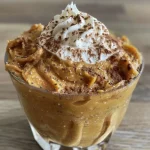 ['Close-up view of creamy pumpkin pudding in a bowl with a smooth texture.', 'Side view of a luscious pumpkin pudding topped with a sprinkle of spices.', 'Rich, velvety pumpkin pudding displayed in a dish, showcasing its creamy consistency.', 'Detailed image of pumpkin pudding, highlighting its inviting orange color and creamy layer.']