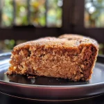 ['Close-up of a moist Greek Milopita apple spice cake with a slice cut out.', 'Side view of a flavorful Milopita loaf adorned with apple slices and nuts.', 'Texture-rich Milopita cake showcasing apples, walnuts, and a cinnamon topping.', 'Slice of Greek apple spice cake with visible raisins and a golden crust.']