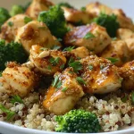 ['A close-up view of a chicken and quinoa bowl with vibrant broccoli and garnished parsley.', 'Juicy chicken served over quinoa with fresh broccoli and a sprinkle of parsley in a bowl.', 'A healthy quinoa bowl featuring sliced chicken breasts, broccoli, and colorful garnishes.', 'A side view of a delicious chicken quinoa bowl, showcasing its fresh ingredients and textures.']