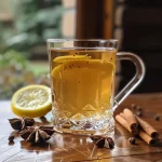 Close-up side view of a non-alcoholic Hot Toddy in a clear glass with a cinnamon stick and lemon slice.