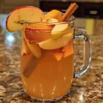 Close-up of a glass of apple cider punch with orange and apple slices.