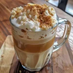 Close-up view of a delicious banana bread latte topped with cold foam and sprinkled with cinnamon.