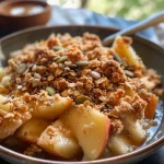 Close-up view of a pear and apple breakfast crumble with a golden oat topping.