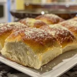 Close-up of golden brown sheet pan dinner rolls, showcasing a soft and fluffy texture.