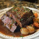 Close-up view of a gingerbread-spiced cider pot roast with carrots and pearl onions.