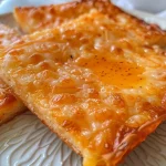 Close-up side view of golden cheese straws with a flaky texture.
