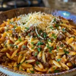Close-up view of a creamy beef and cheddar orzo dish in a bowl.